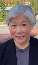 A woman with gray hair sitting outside in the sun.