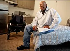 A man sitting on top of a bed in a room.