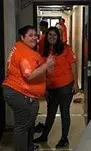 Two women in orange shirts posing for a picture.