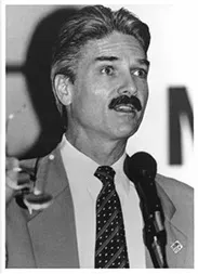 A man in a suit and tie holding a microphone.