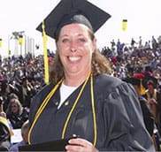 A woman in graduation cap and gown smiling for the camera.